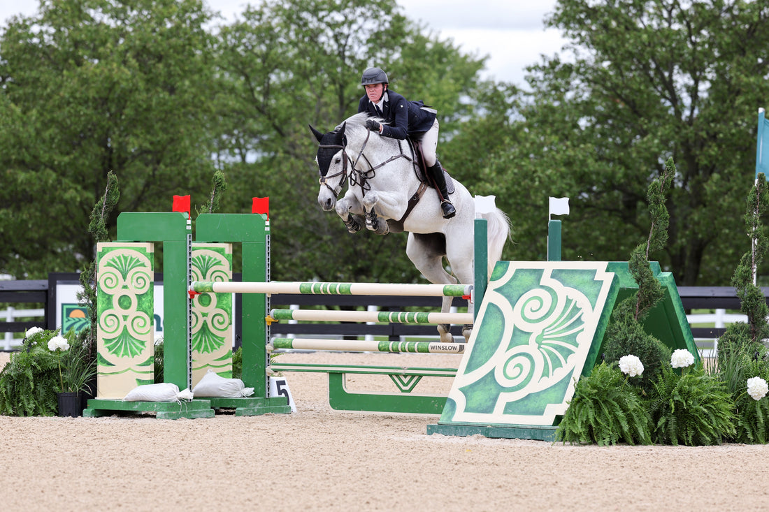 Karston Gundry jumping his horse over a green jump at a show