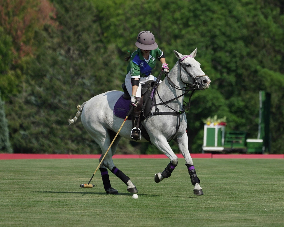 Polo player riding horse across field