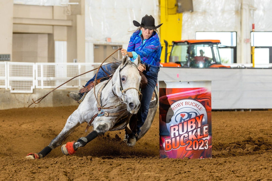 Barrel racer and grey horse going around a barrel at a barrel race