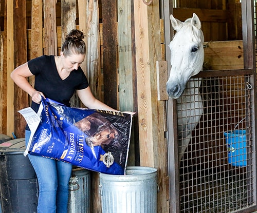woman feeding horse Essential K feed