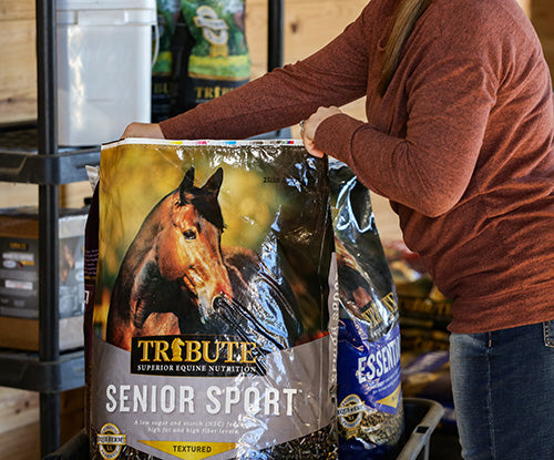 woman opening bag of tribute senior sport horse feed
